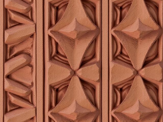 Detailaufnahme eines maßgefertigten Terrakotta-Fassadenelements an einem historischen Gebäude.